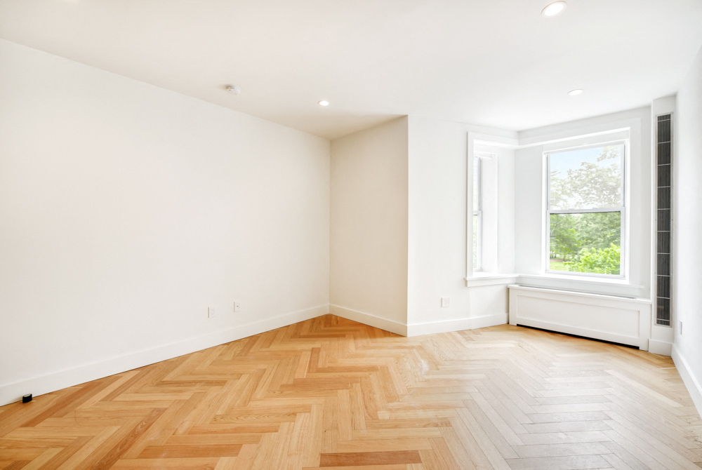 an empty room with wood flooring and a window